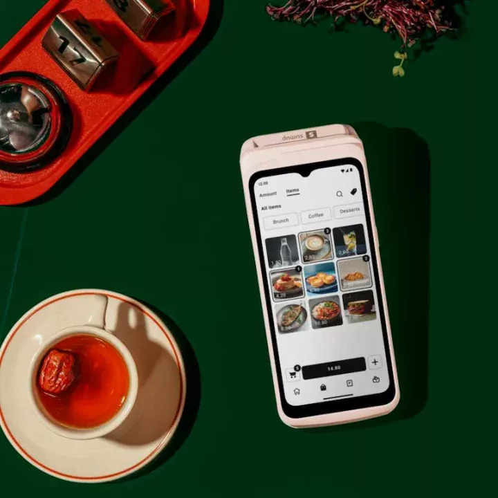 SumUp Terminal All-in-One-Kartenterminal in Weiß - Draufsicht auf grünem Hintergrund mit Kaffeetasse